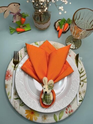 Mesa decorada para a Páscoa, com guardanapo laranja em formato de ovo
