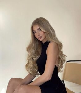 Jess Junt, com vestido preto e cabelo loiro com ondas