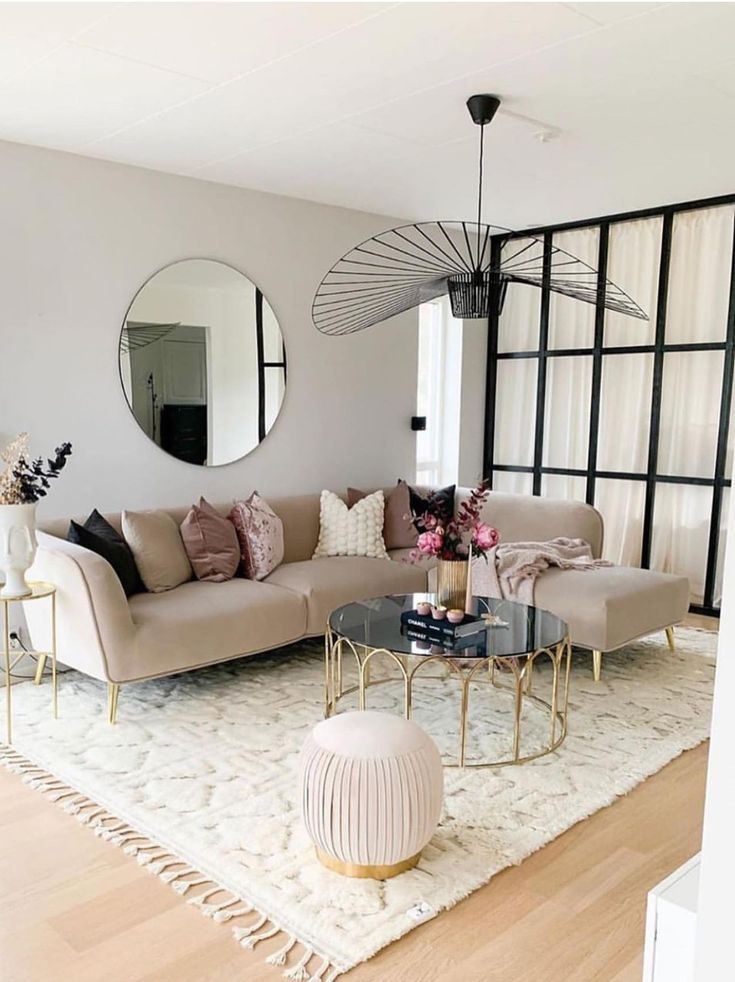 Sala de estar com sofá claro, grande tapete e espelho redondo na parede atrás do sofá