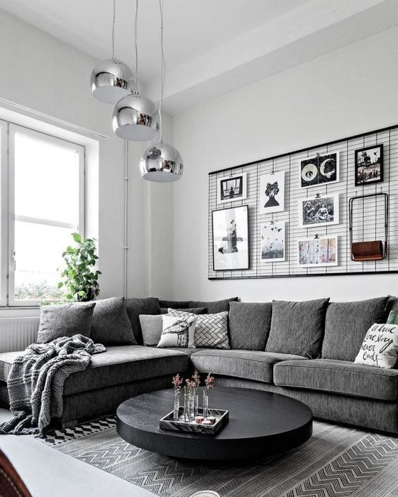 Sala em tons de branco, cinza e preto com pendentes prateados