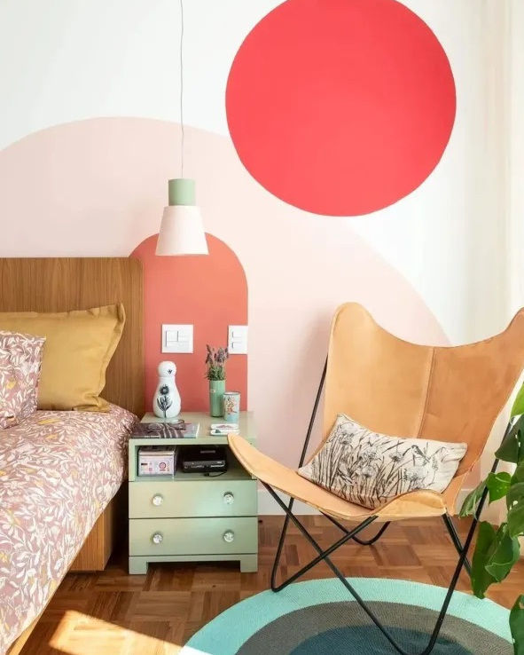 Quarto com parede pintada de tons de rosa na cabeceira e cadeira de couro