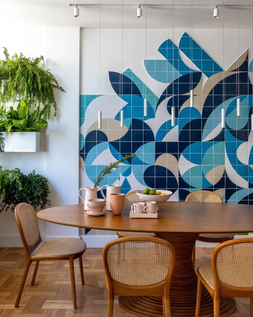 Sala de jantar com mesa de madeira oval com cadeiras com assento e encosto de palhinha, e parede colorida em tons de azul