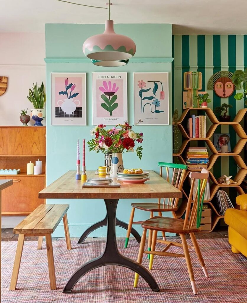Sala de jantar com mesa de madeira e ferro e parede verde-menta com quadros
