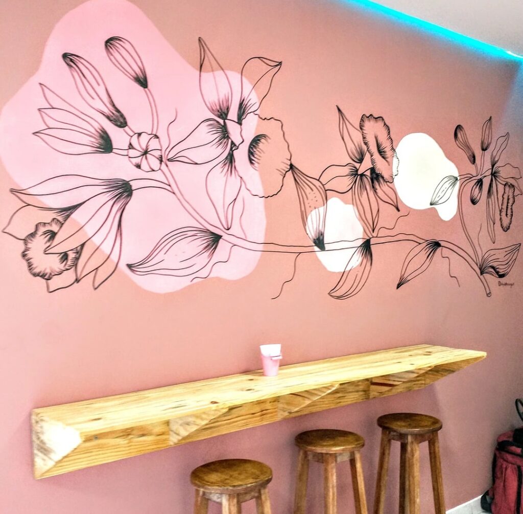Parede rosa com flores, prateleira e bancos em madeira