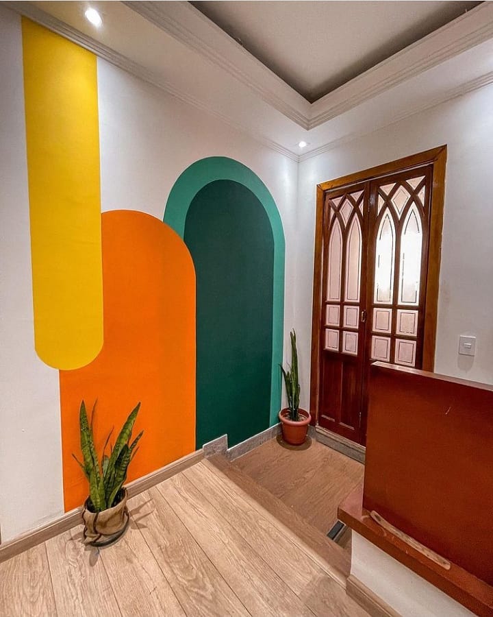 Espaço com pinturas orgânicas em verde, laranja e amarelo na parede