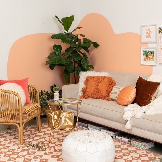 Sala de estar com sofá cinza, cadeira de vime, e pintura orgânica em duas paredes