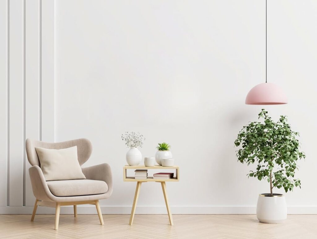 Ambiente com parede branca, pendente rosa, poltrona e itens em cor neutra