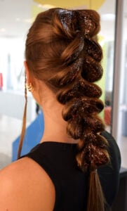 Mulher de pele clara de costas com cabelo trançado com glitter
