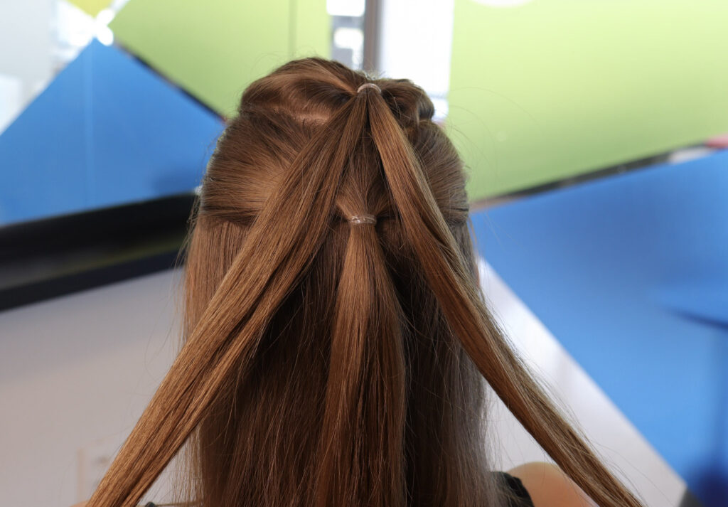 Mulher de costas com cabelo castanho e dois pequenos rabos de cavalo