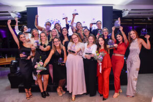 Mulheres segurando troféu na mão e sorrindo
