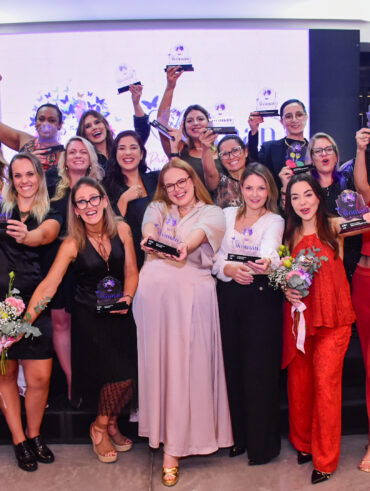Mulheres segurando troféu na mão e sorrindo