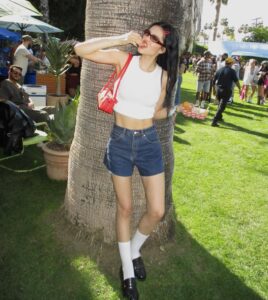Amelia Gray com regata branca, bermuda jeans e mocassim com meia.