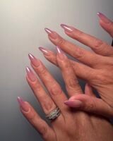 Mãos de pele clara, com anel em prata e unha amendoada ombré rosa-claro