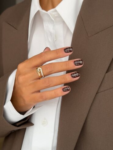 Mão de pele branca com esmalte marrom e nail art com estampa de cobra