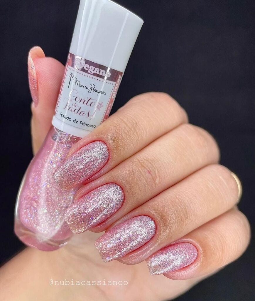 Mão de pele clara, com unha quadrada rosa com glitter 