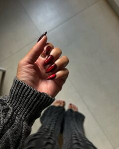 Mão de pele preta, com anel em prata e unha vermelho-cereja com design aura