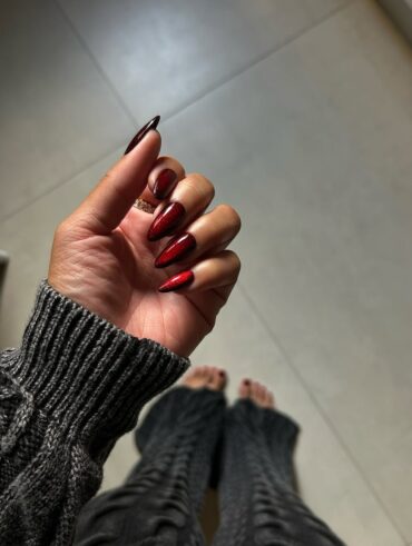 Mão de pele preta, com anel em prata e unha vermelho-cereja com design aura