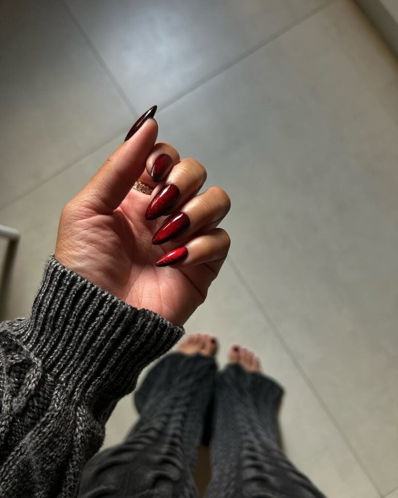 Mão de pele preta, com anel em prata e unha vermelho-cereja com design aura