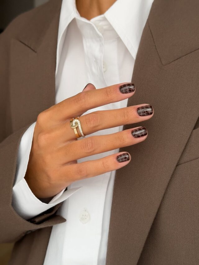 Mão de pele branca com esmalte marrom e nail art com estampa de cobra