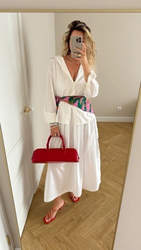 Mulher jovem e magra com look com lenço na cintura.