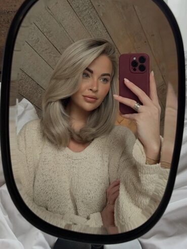 Mulher de pele clara, com suéter neutro e cabelo loiro médio