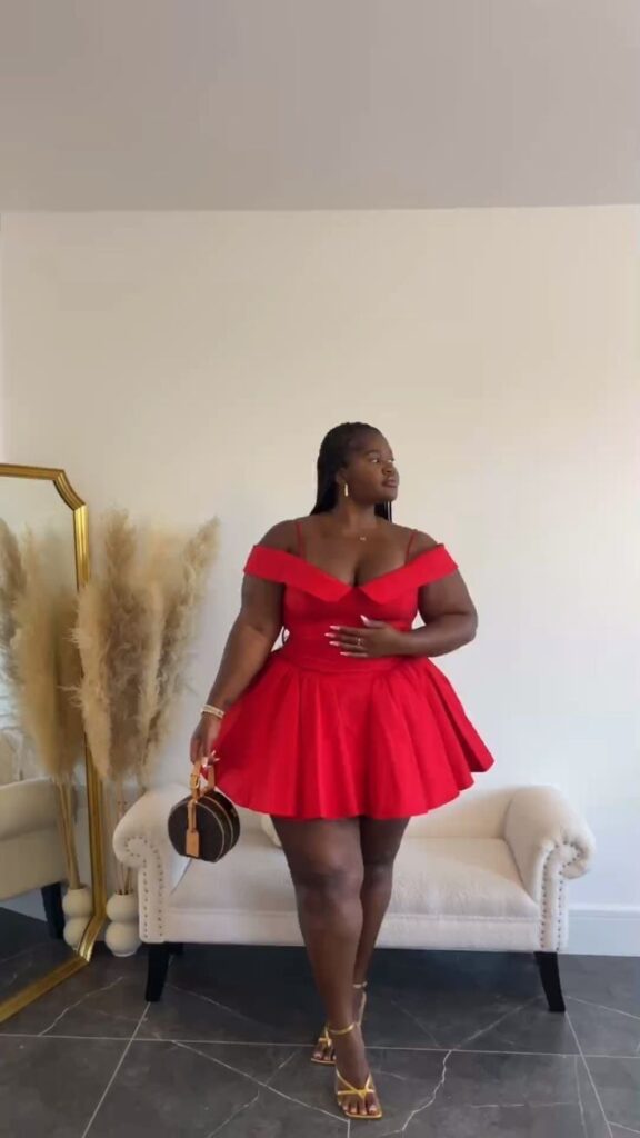 Mulher adulta com vestido vermelho curto e rodado. Ela usa salto alto dourado e segura uma bolsa redonda preta.