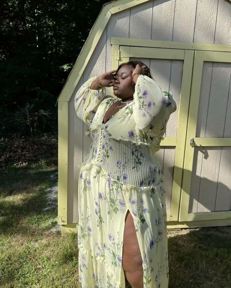 Mulher jovem com pele escura. Ela veste modelo floral longo com manga comprida.