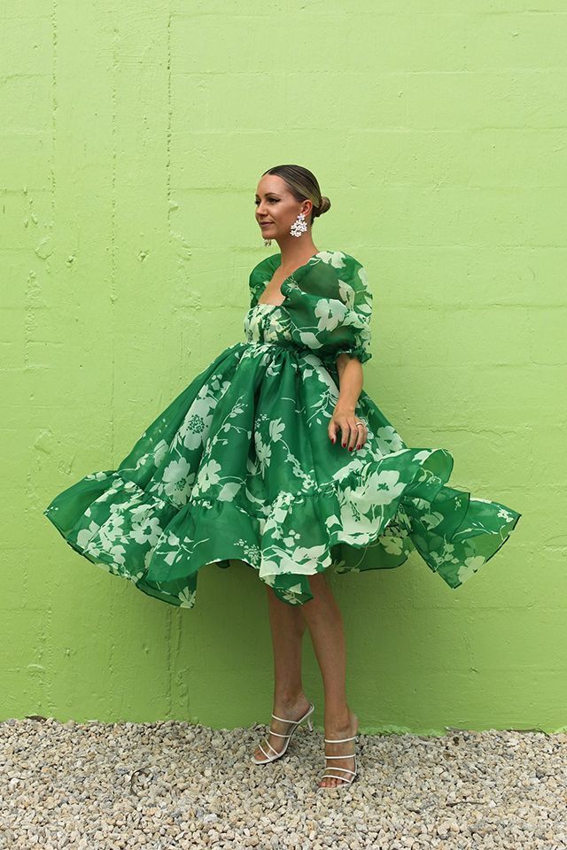 Mulher jovem, magra e de pele clara com vestido midi de cor verde e flores brancas.