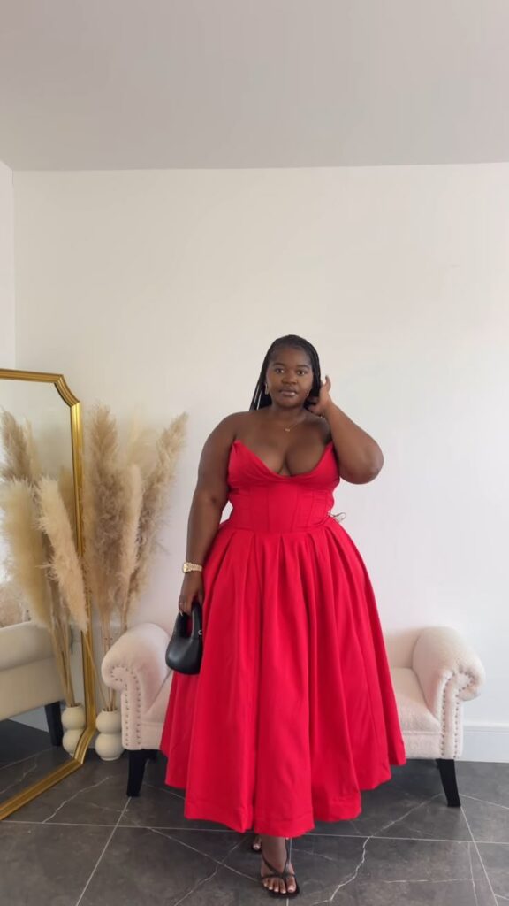 Mulher jovem com pele negra e vestido longo vermelho sem alças.