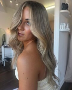 Mulher de pele clara, com blusa branca, e cabelo loiro acinzentado