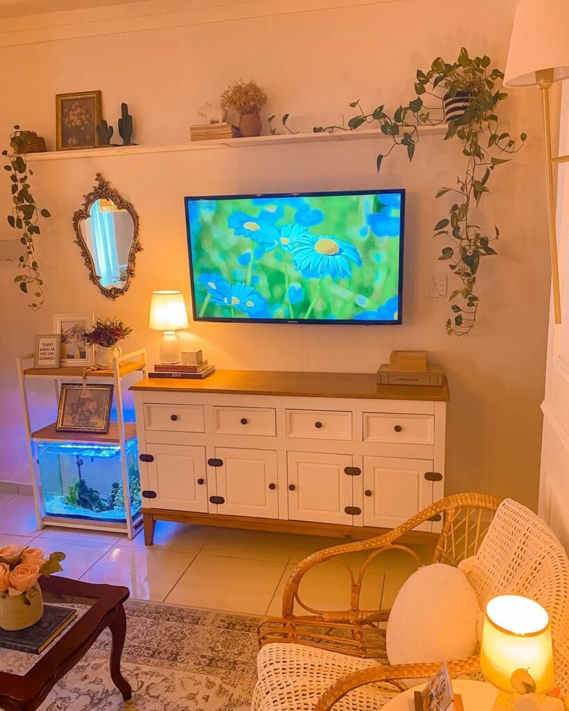 Sala de estar com balcão branco e base amadeirada, espelho provençal e aquário