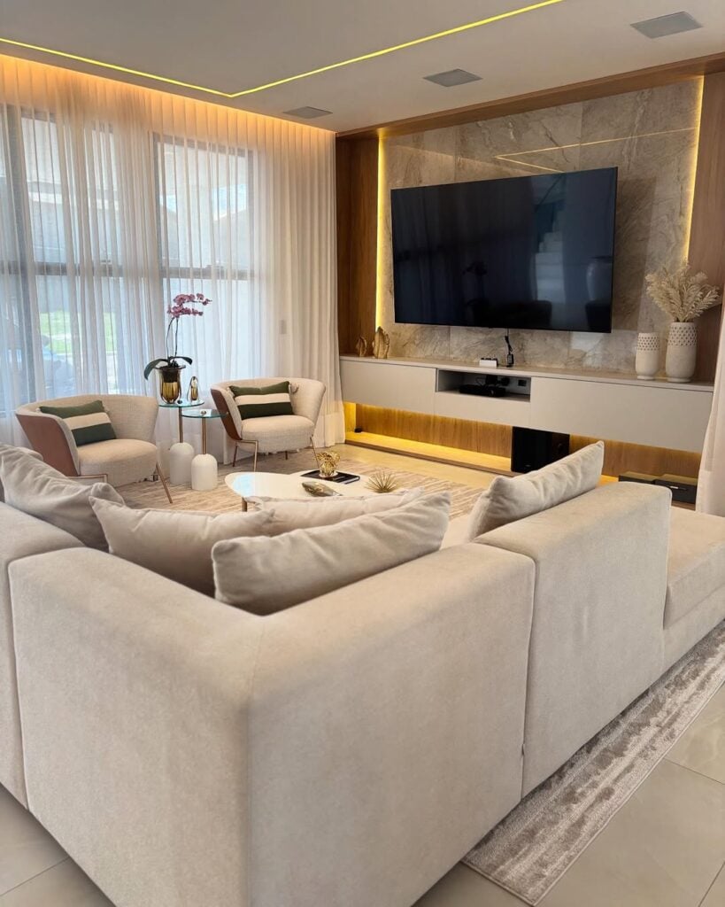 Sala de estar com sofá em cores neutras e grande tv na parede