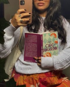 Mulher de pele preta, com suéter. Ela está segundo um livro
