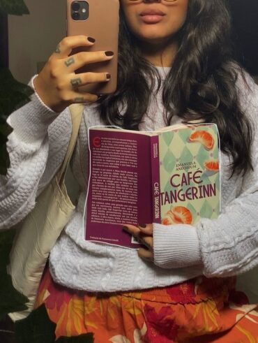 Mulher de pele preta, com suéter. Ela está segundo um livro