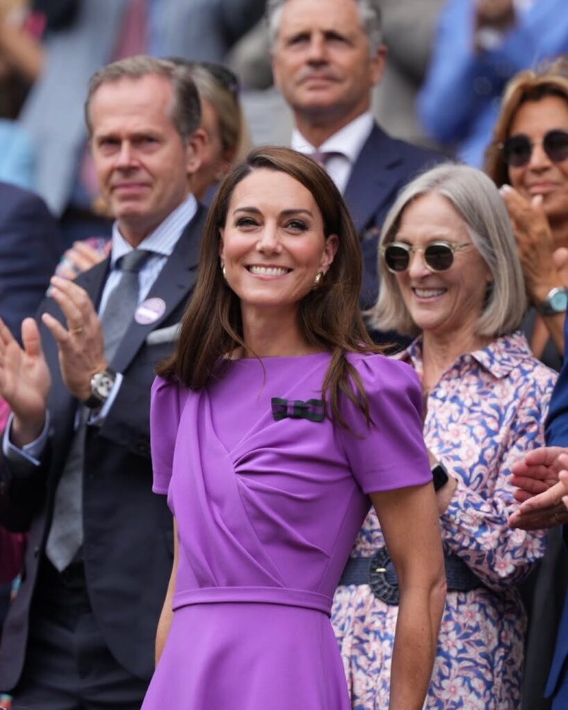 Kate Middleton, com vestido roxo e cabelo castanho