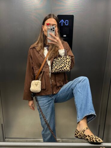 Mulher jovem e magra com look marrom e calça jeans. Ela usa bolsa e sapatilha animal print.