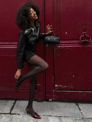 Mulher jovem com look todo preto e meia-calça com bolinhas