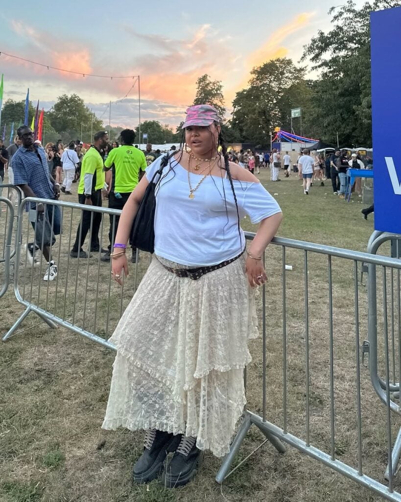 Mulher gorda e de pele preta-clara, com blusa branca e saia de renda com cinto