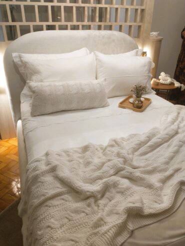 Quarto com cabeceira estofada e jogo de cama branco, com bandeja de bambu
