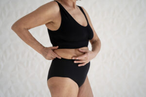 Mulher madura segurando a barriga com gordura abdominal