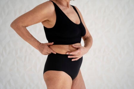 Mulher madura segurando a barriga com gordura abdominal