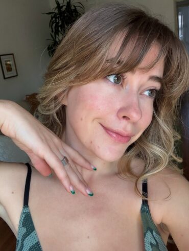 Mulher de pele clara, com regata, rosácea nas bochechas e cabelo loiro