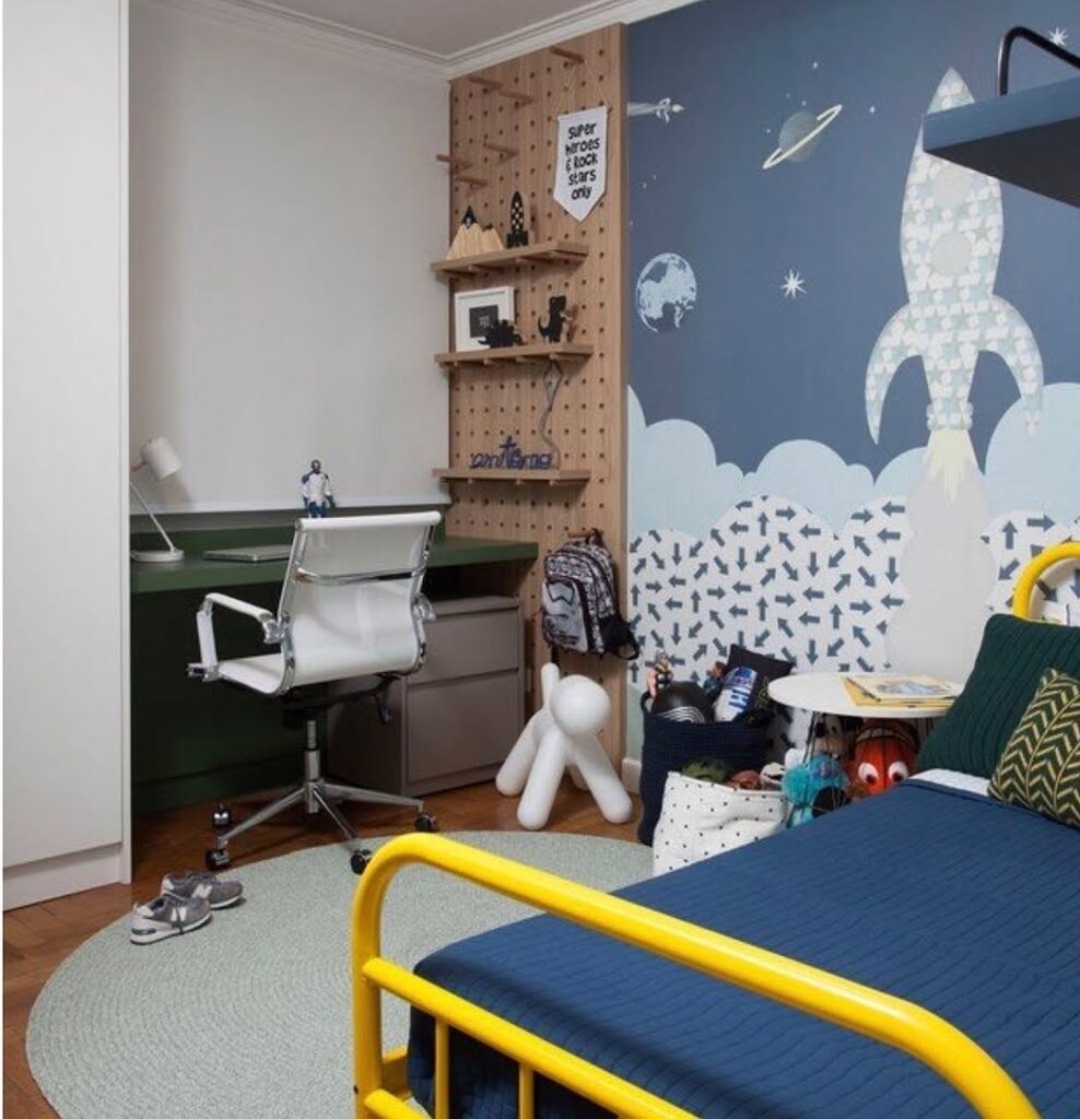 Quarto infantil com temática de espaço, cama amareça e espaço de estudo