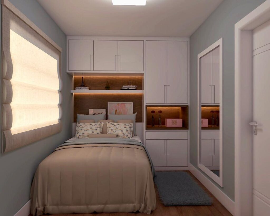 Quarto com armários brancos, cama embutida no roupeiro e espelho retangular na parede