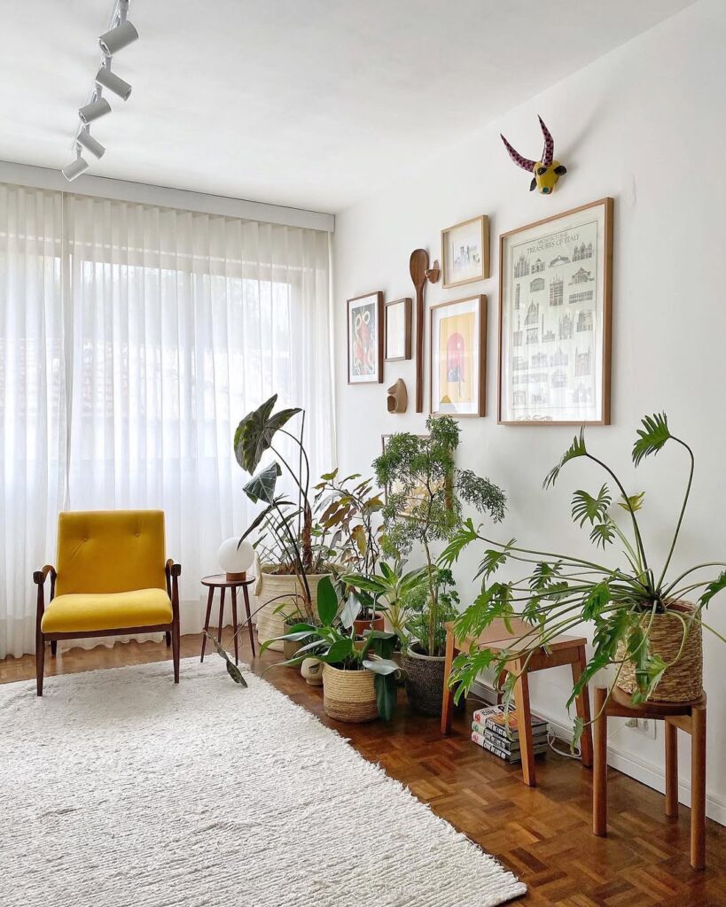 Sala de estar aconchegante com plantas, poltrona amarela, quadros na parede e cortina