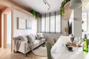 Sala de estar pequena com quadros, TV e sofá e cozinha com península