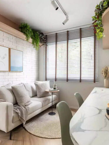 Sala de estar pequena com quadros, TV e sofá e cozinha com península