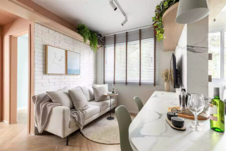Sala de estar pequena com quadros, TV e sofá e cozinha com península