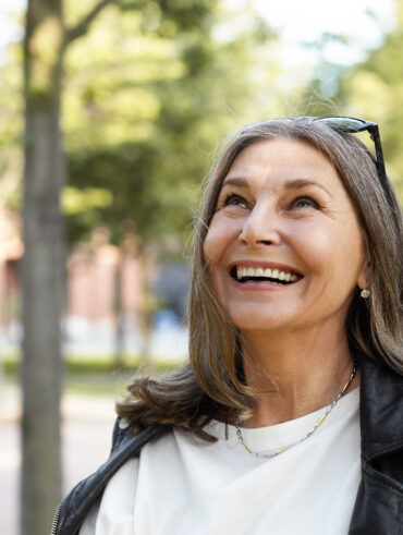 Mulher de 40 anos e cabelos grisalhos sorrindo
