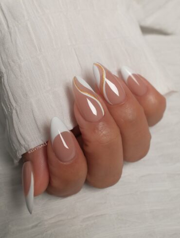 Mão de pele clara, com unha amendoada branca com linhas fluidas em branco e dourado